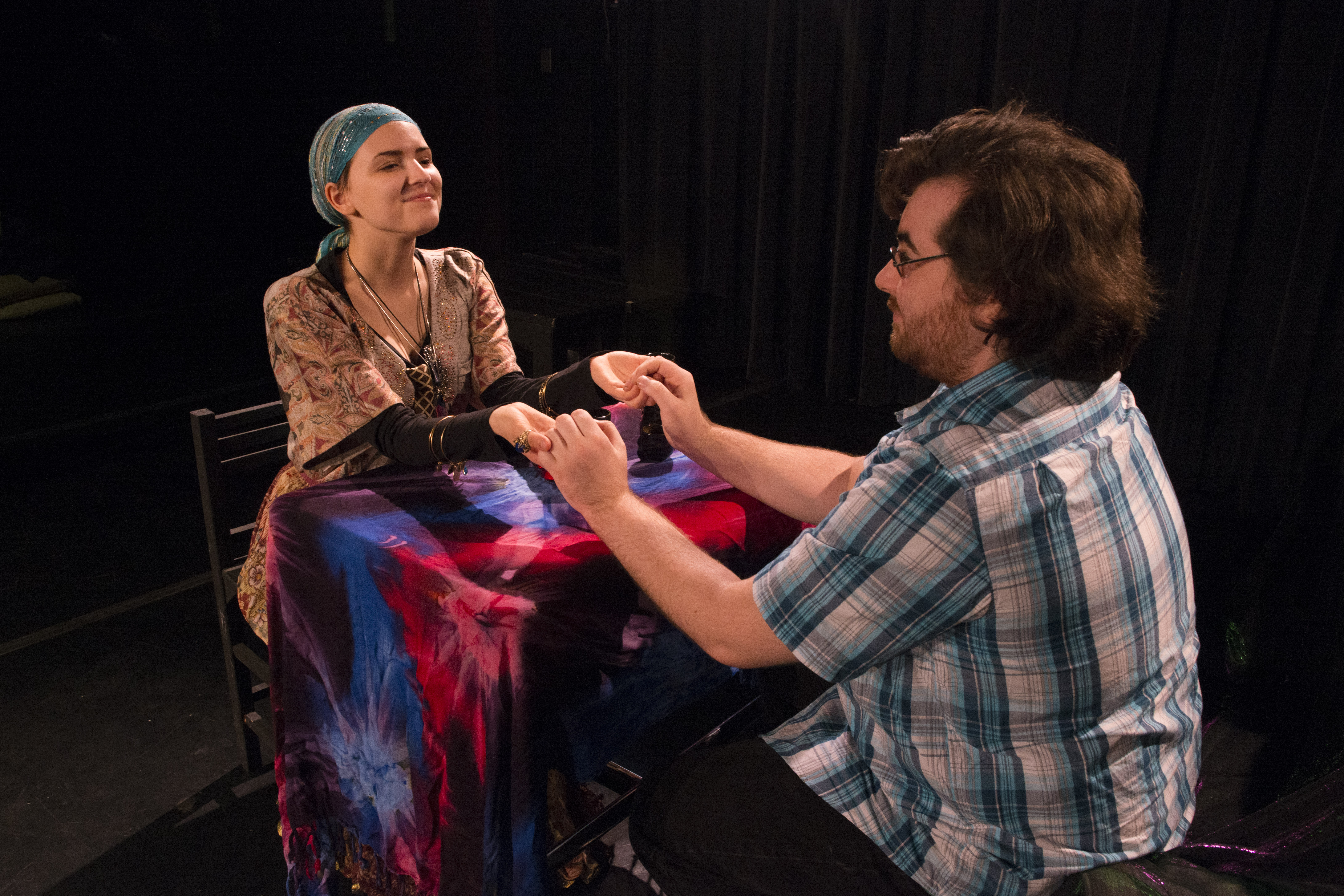A female actress dressed as a fortune teller holding a male actors hands