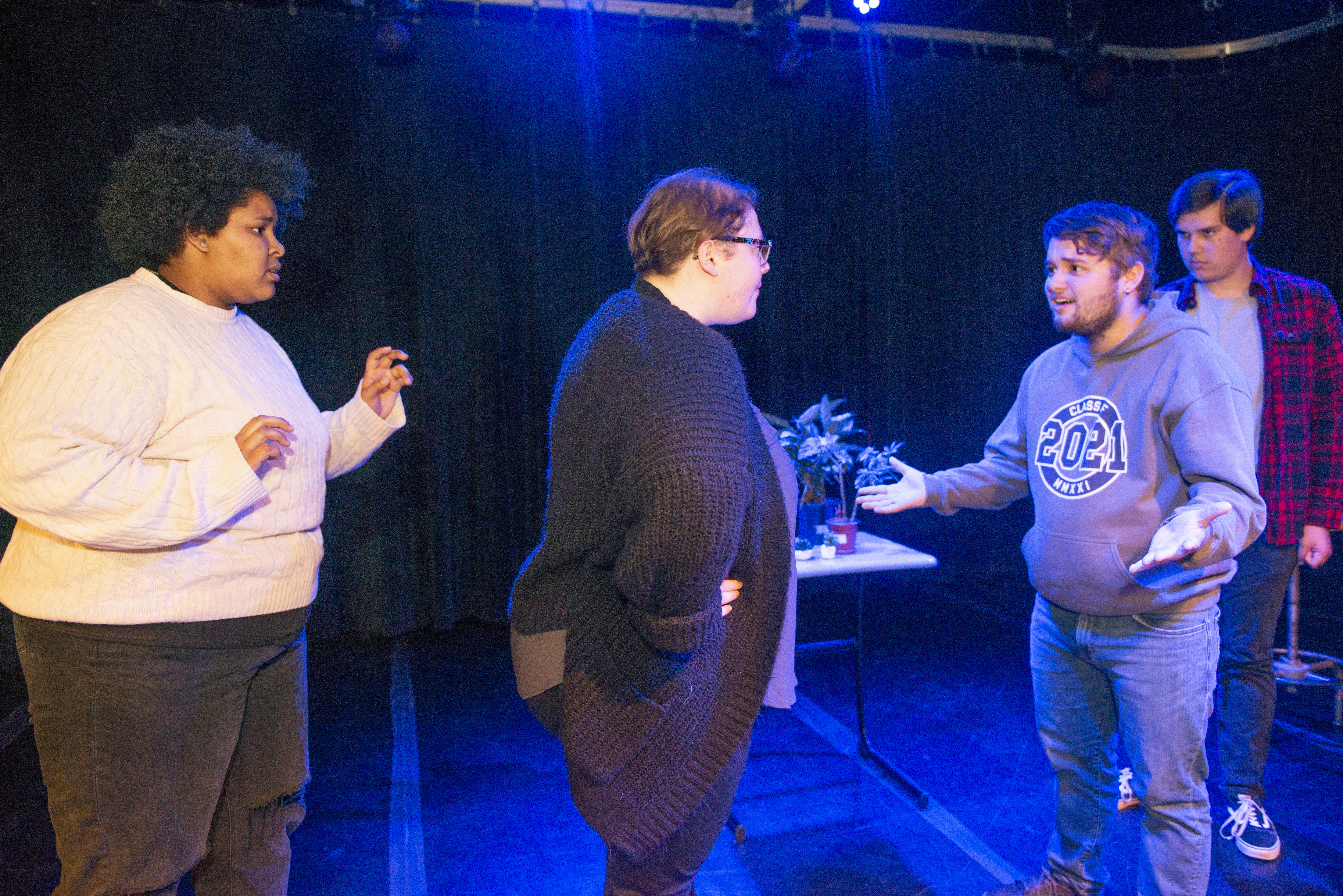 Four theater students standing having a conversation