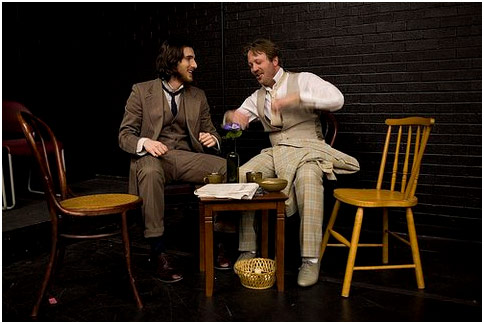 Two actors in suits sitting in chairs talking