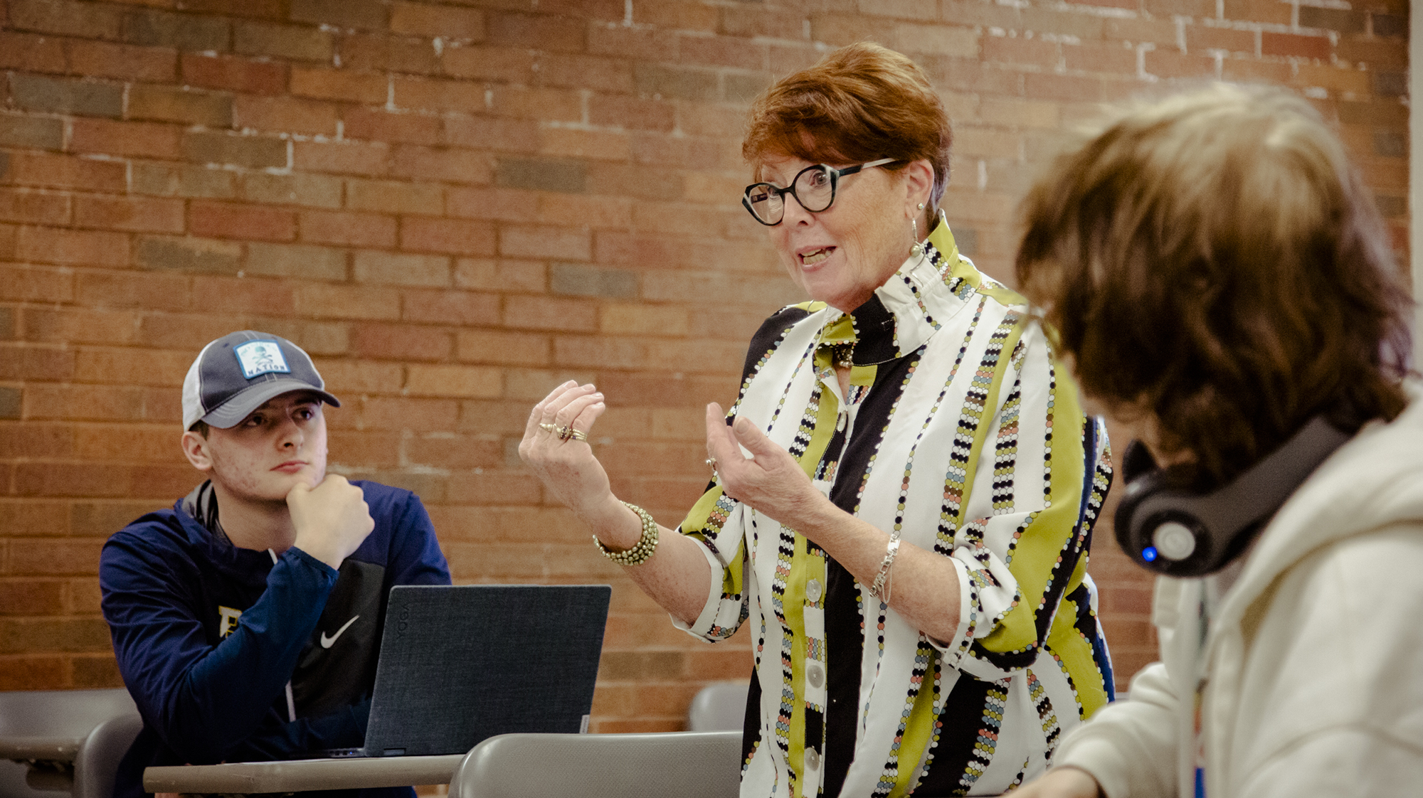 a professor speaking to a class, 2 people are seen listening to the professor