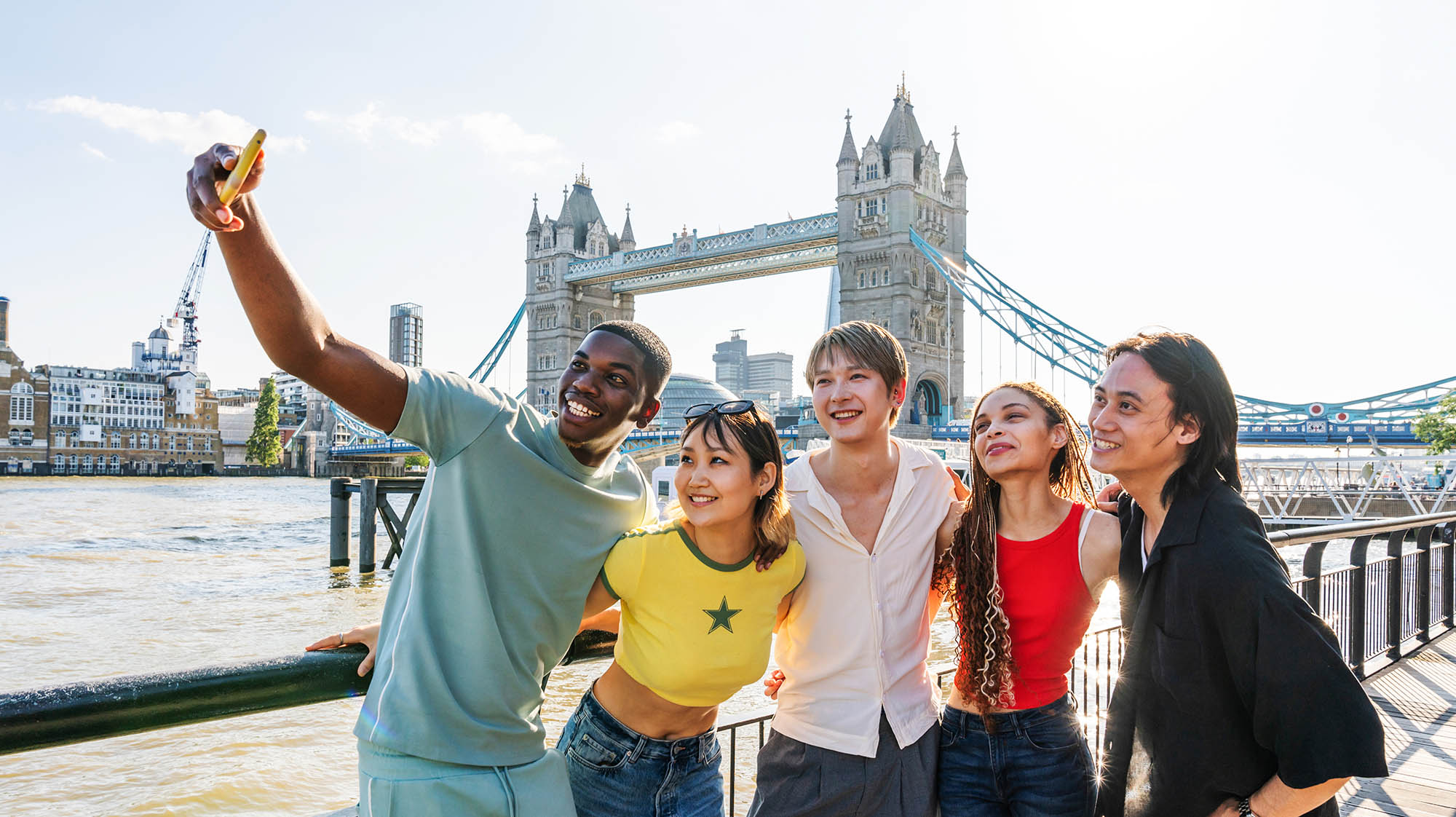 Group of students taking a selfie in front of London's Tower Bridge during a study abroad or travel experience