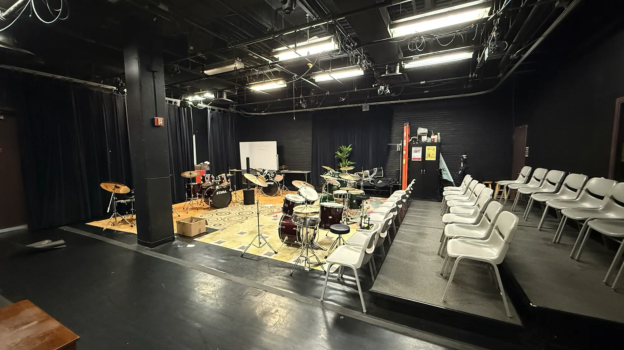 a blackbox theatre with seats and drum kits in it