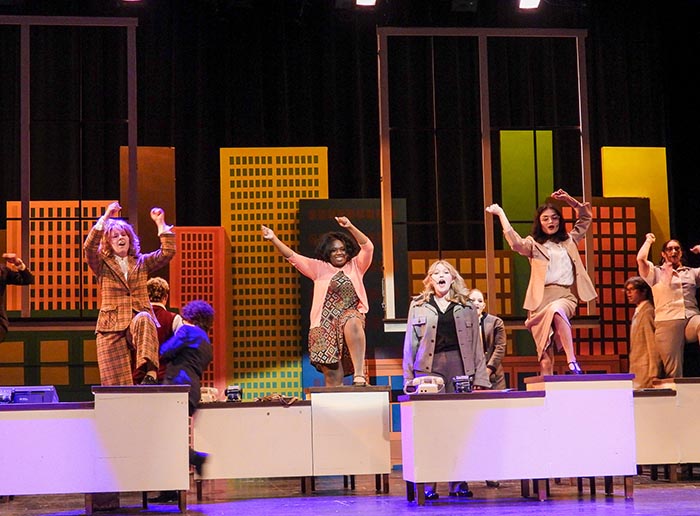 students performing on stage with their hands up in the air