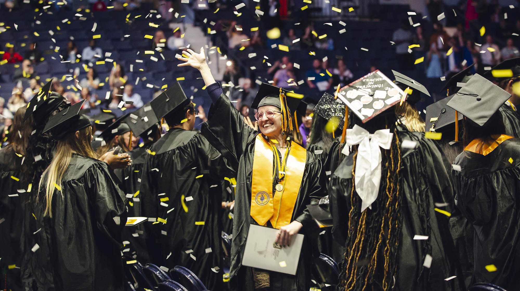 mcc students wearing grad caps and gowns, one student is facing the camera and smiling