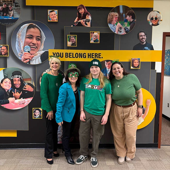students and faculty posing in front of a mural