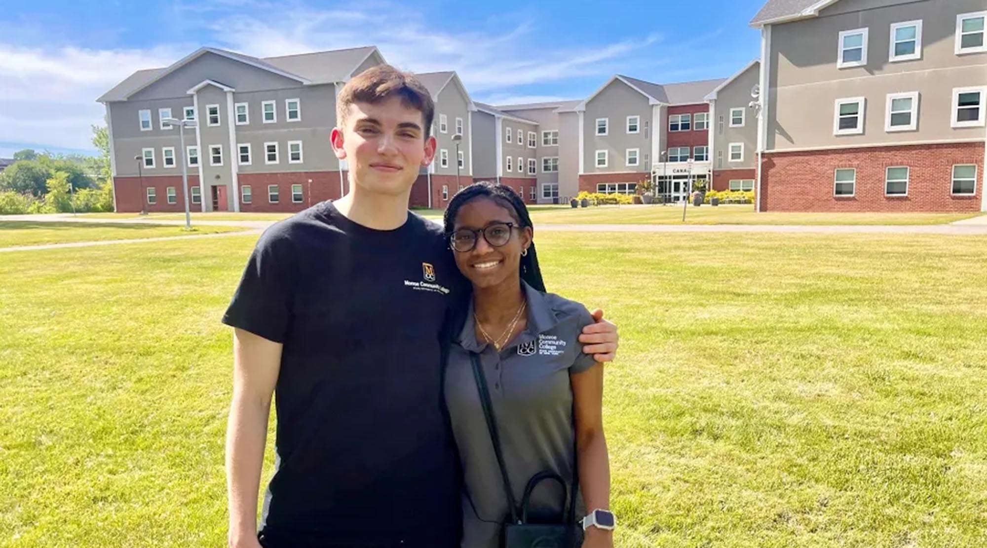 Two Monroe Community College students stand together on the lawn in front of the Canal residence hall.